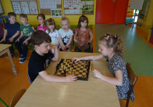 Chłopiec z dziewczynką grają w szachy.